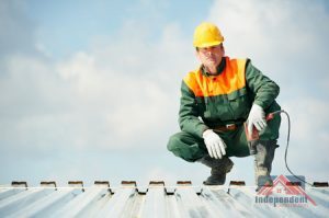 a roofer crouched on a Metal Roof