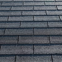 A low-angle view of a traditional roof with 3-tab asphalt shingles